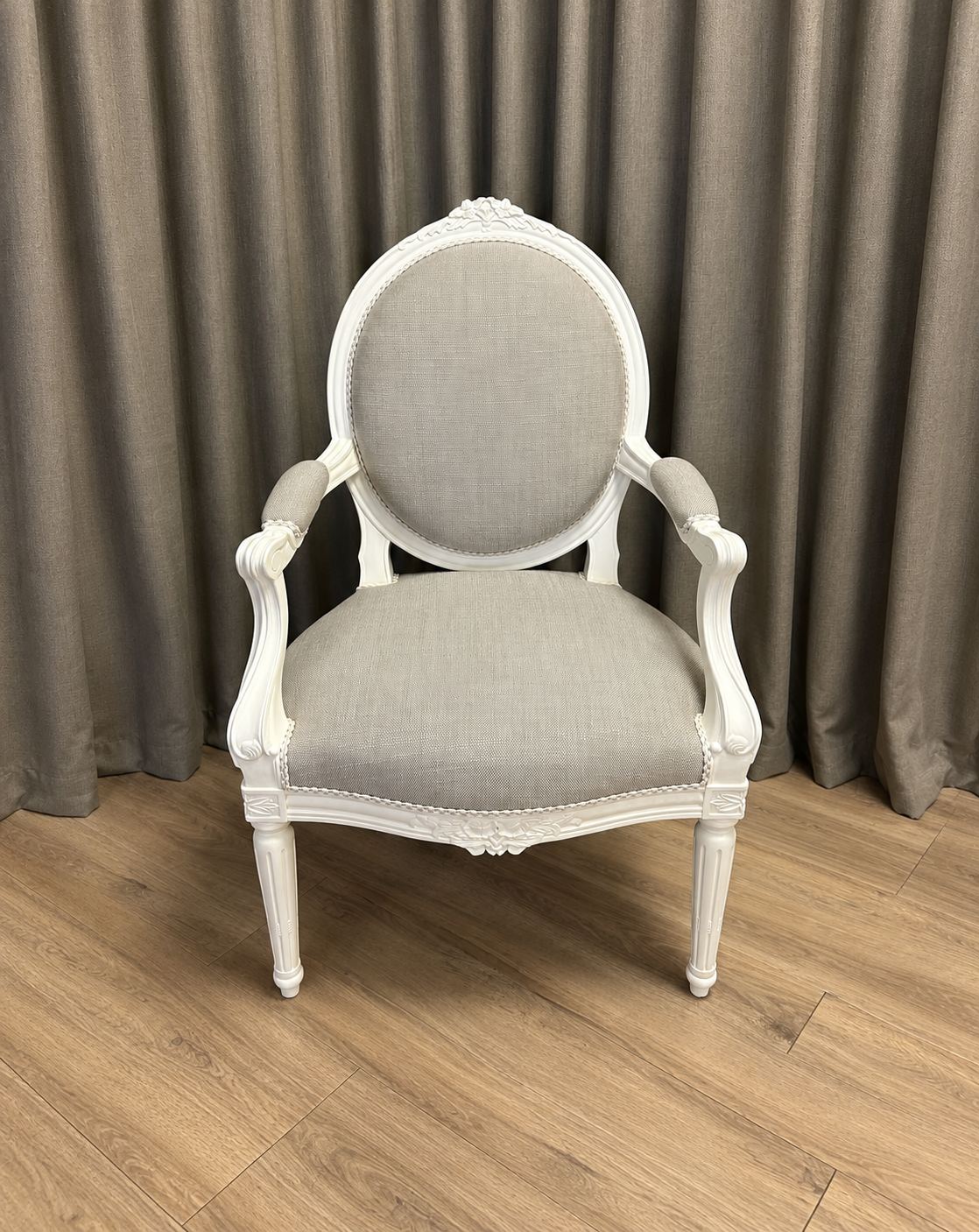 Fauteuil médaillon de style Louis XVI au bois blanc sculpté, refait en tissu gris